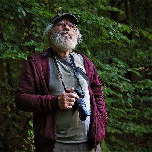 Poeta Michał Majewski stoi na tle zieleni
