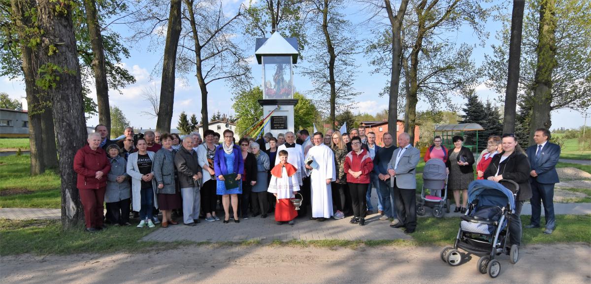 grupa ludzi stojąca przed kapliczką