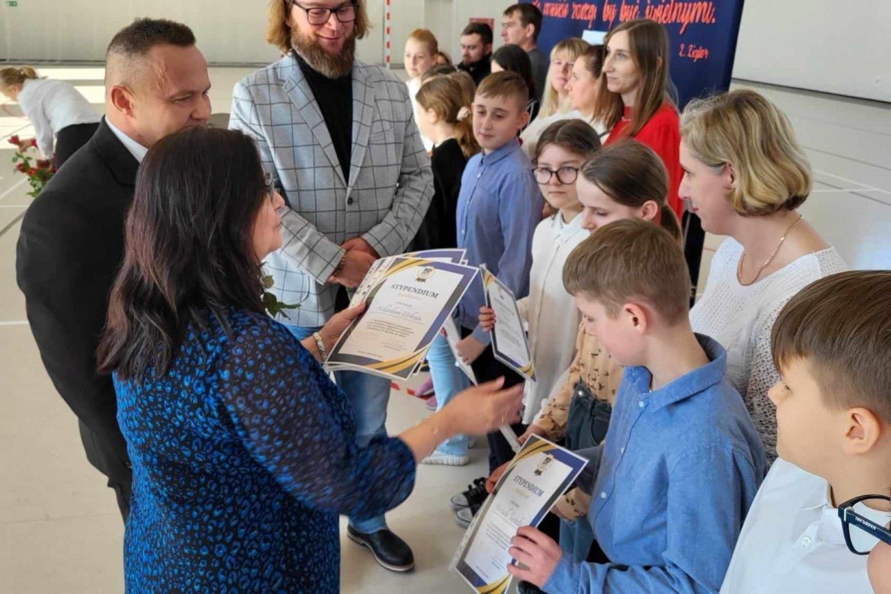 Wójt i dyrektor szkoły wręczają dyplomy dzieciom