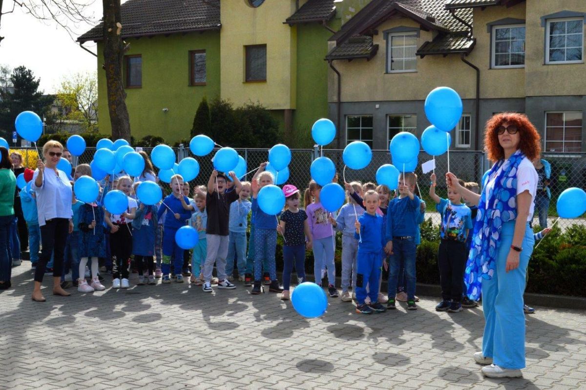 dzieci ubrane na niebiesko z niebieskimi balonikami naszerują na ulicach Zblewa