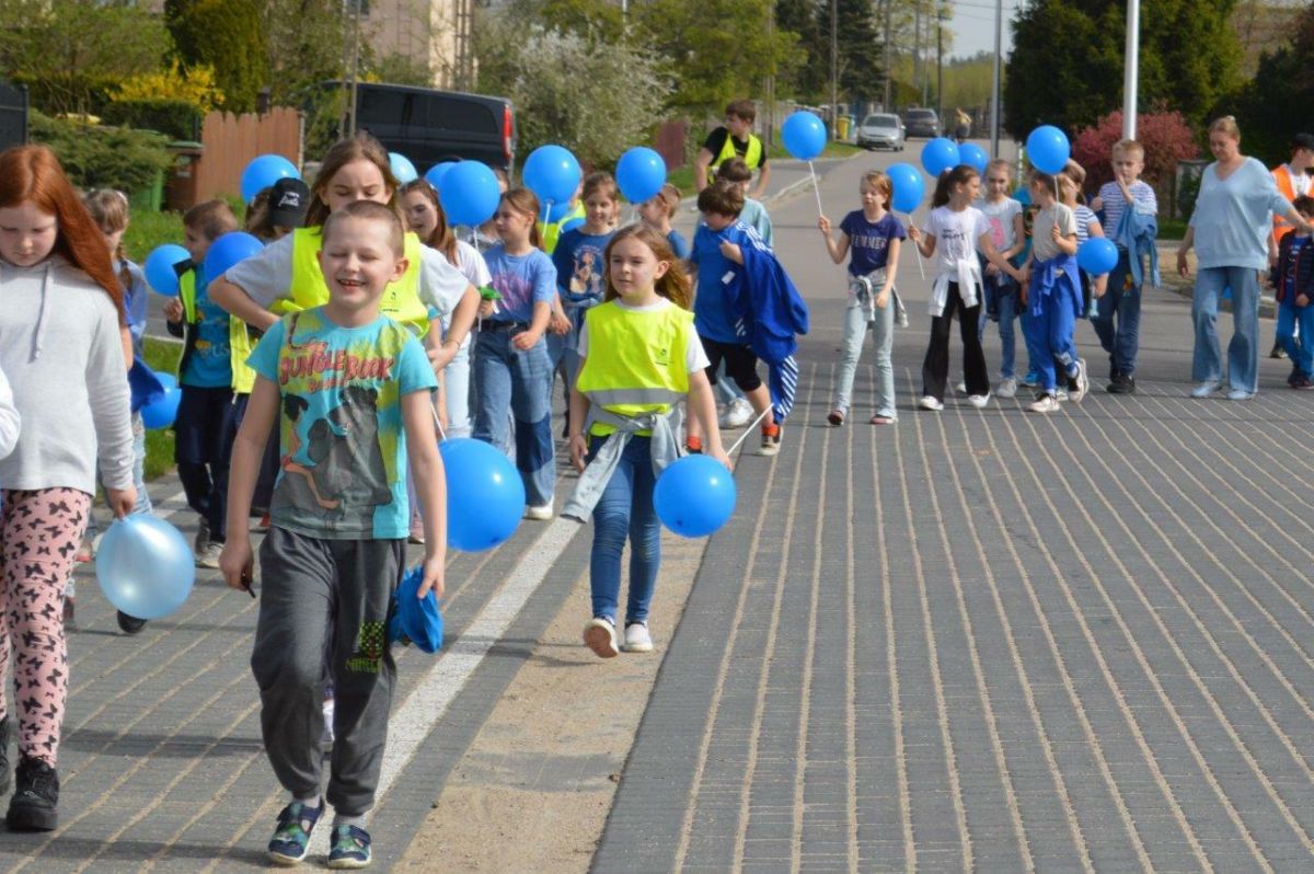 dzieci ubrane na niebiesko z niebieskimi balonikami naszerują na ulicach Zblewa