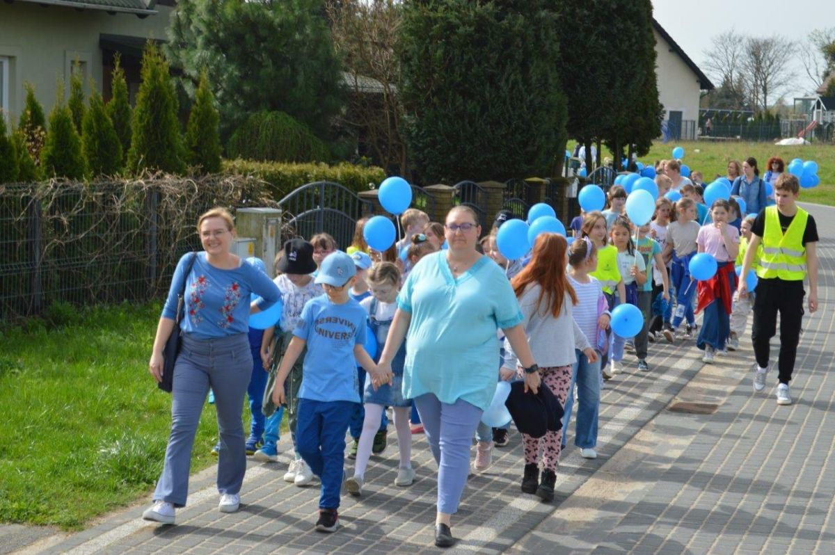 dzieci ubrane na niebiesko z niebieskimi balonikami naszerują na ulicach Zblewa