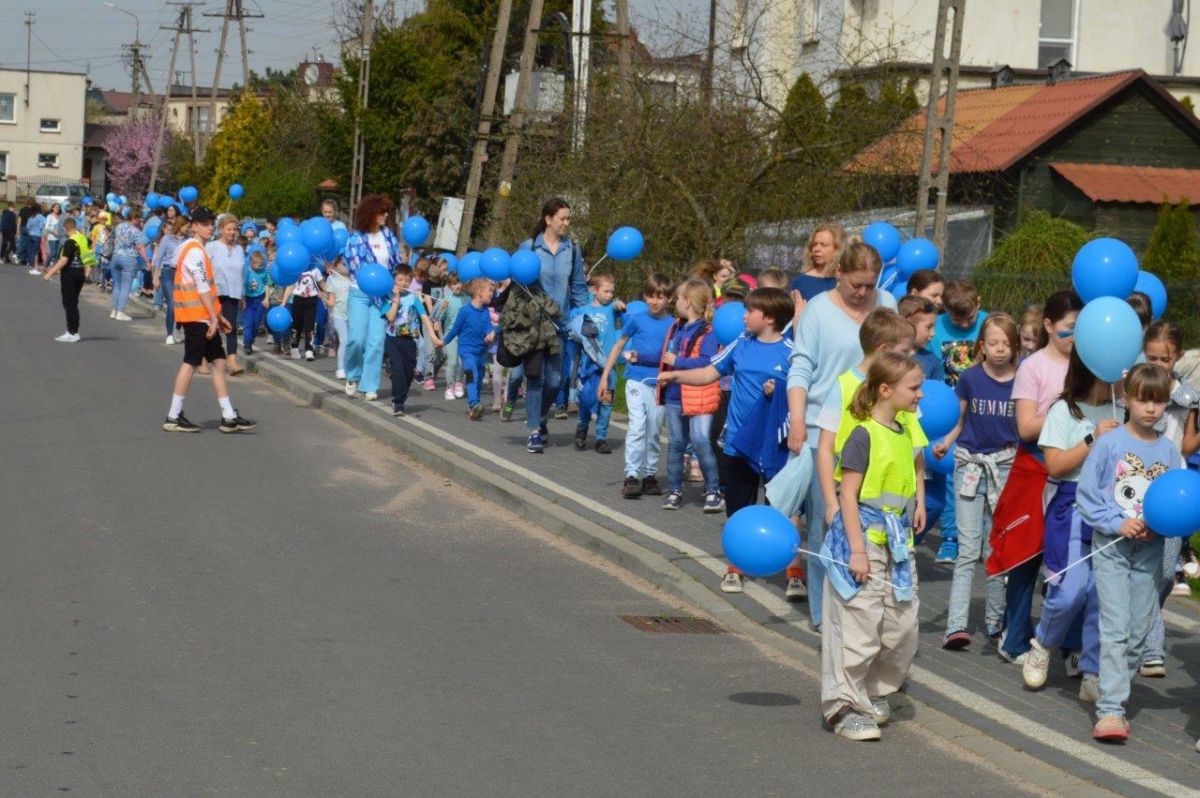 dzieci ubrane na niebiesko z niebieskimi balonikami naszerują na ulicach Zblewa