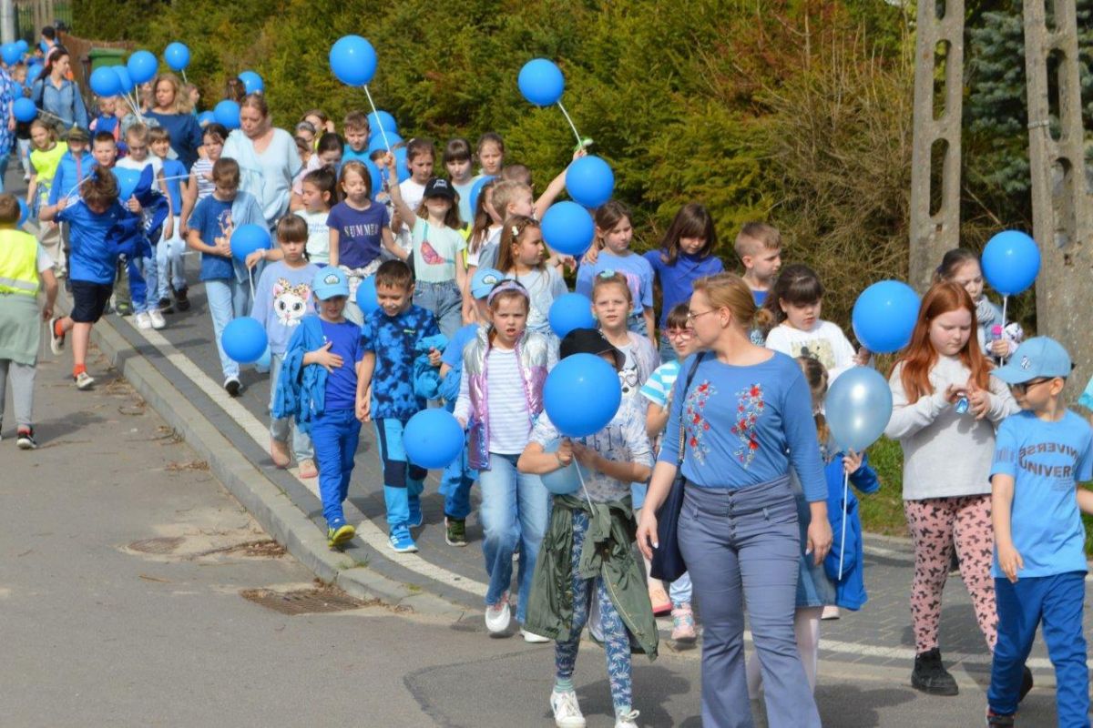 dzieci ubrane na niebiesko z niebieskimi balonikami naszerują na ulicach Zblewa